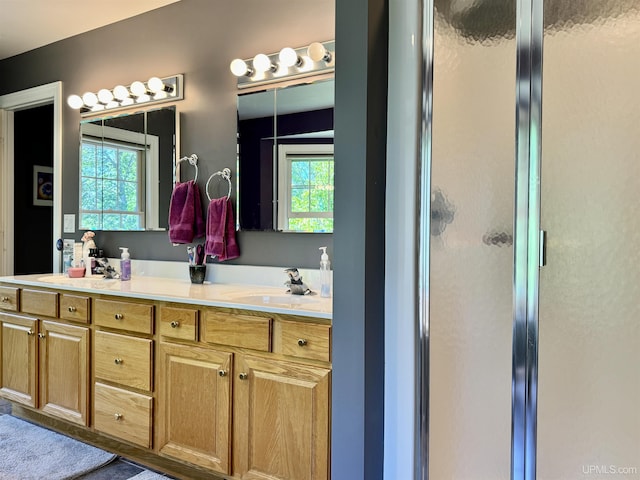 bathroom featuring a sink, a stall shower, and double vanity