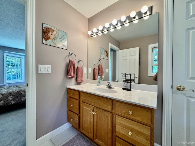 bathroom with baseboards, ensuite bath, vanity, and tile patterned flooring