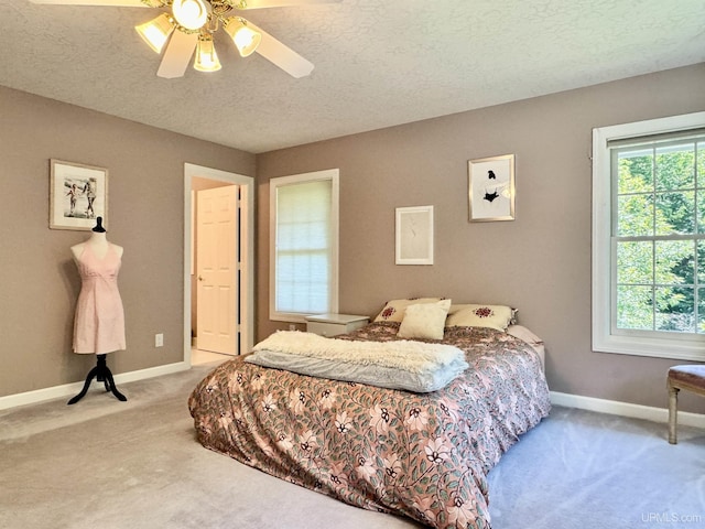 bedroom featuring baseboards, light colored carpet, a ceiling fan, and a textured ceiling