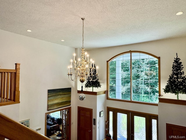 foyer entrance with recessed lighting, a textured ceiling, and an inviting chandelier