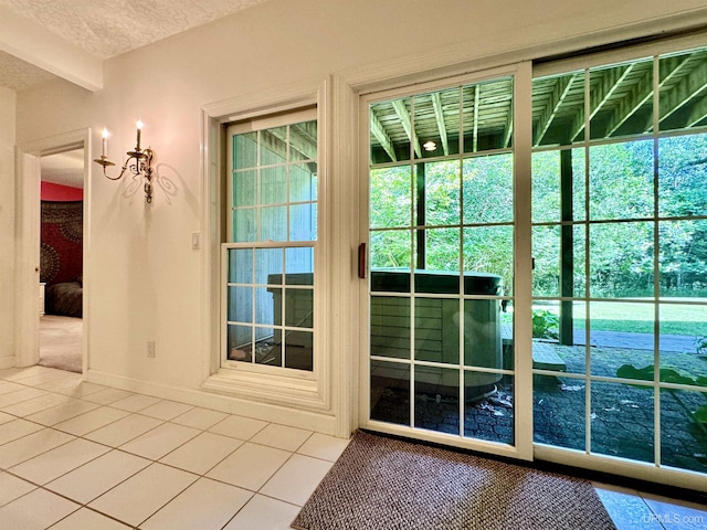 doorway to outside featuring tile patterned flooring, baseboards, and a textured ceiling