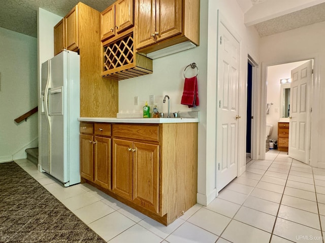 kitchen featuring light tile patterned floors, brown cabinets, and white refrigerator with ice dispenser