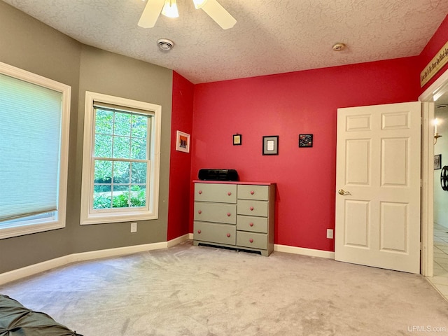 unfurnished bedroom with light colored carpet, baseboards, and a textured ceiling