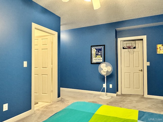 interior space with ceiling fan, carpet, baseboards, and a textured ceiling