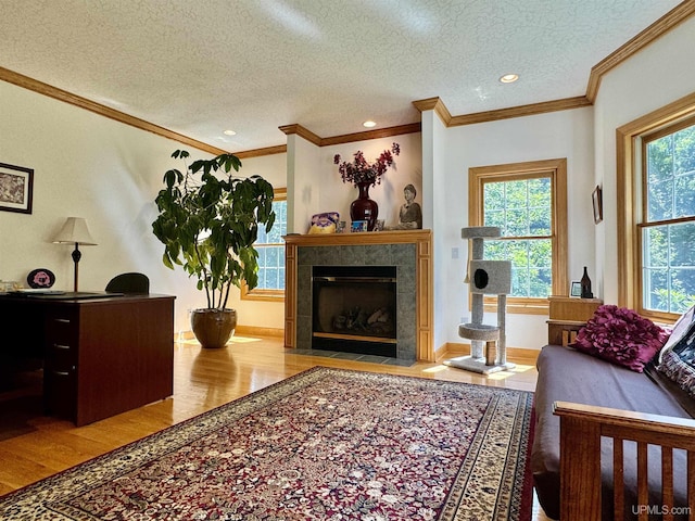 living room with a textured ceiling, wood finished floors, a tiled fireplace, and ornamental molding