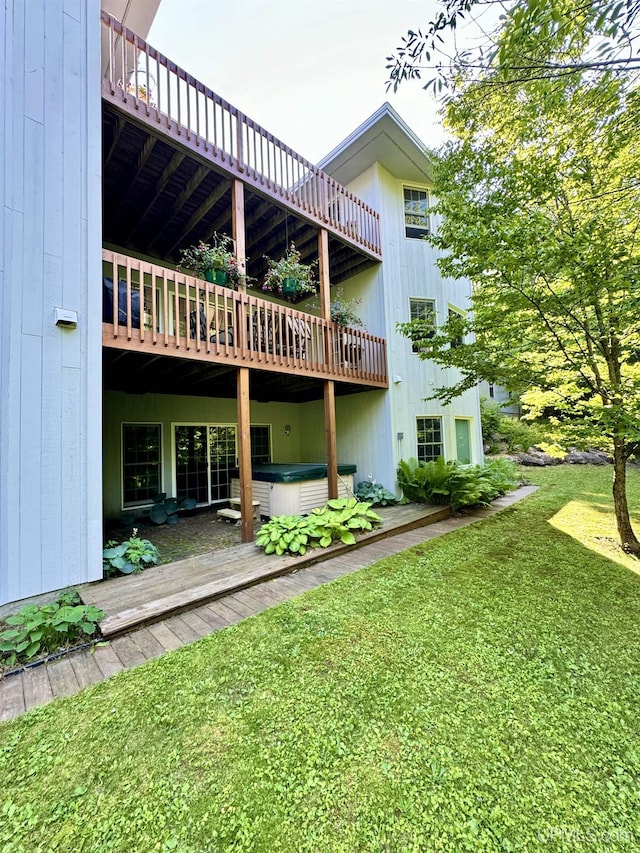 rear view of house featuring a lawn and a hot tub