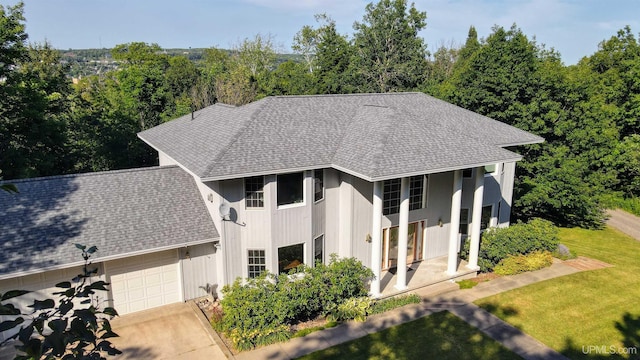 view of front of property with a front yard, a garage, driveway, and a shingled roof