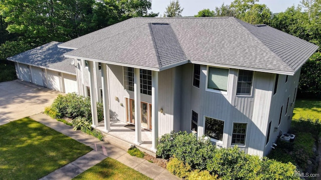 view of front of house with a garage, a front lawn, and a shingled roof