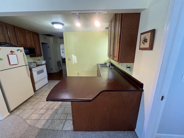 kitchen featuring a breakfast bar, sink, white appliances, and kitchen peninsula