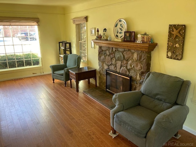 sitting room featuring a stone fireplace and hardwood / wood-style floors