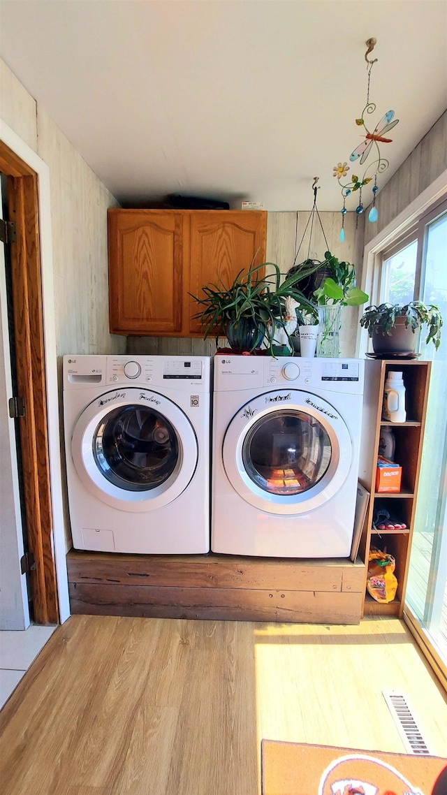 laundry room with cabinets, washing machine and dryer, and light hardwood / wood-style flooring