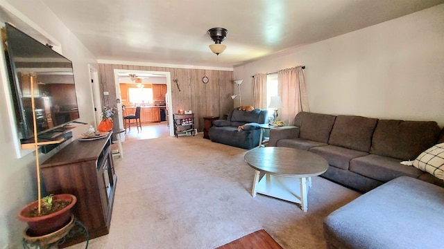 carpeted living room featuring ceiling fan and wood walls