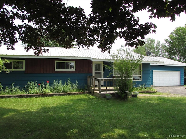 ranch-style house featuring a front yard, metal roof, driveway, and an attached garage