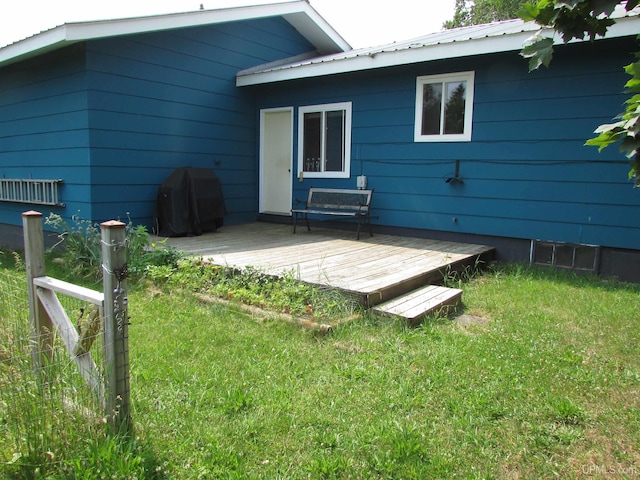 rear view of house with a yard, metal roof, a wooden deck, and fence