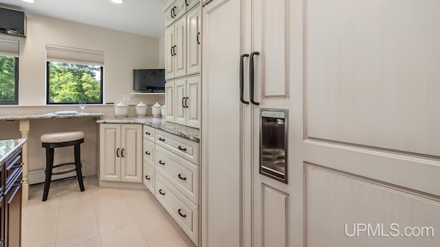 kitchen featuring a kitchen breakfast bar, baseboard heating, light stone counters, and light tile patterned floors