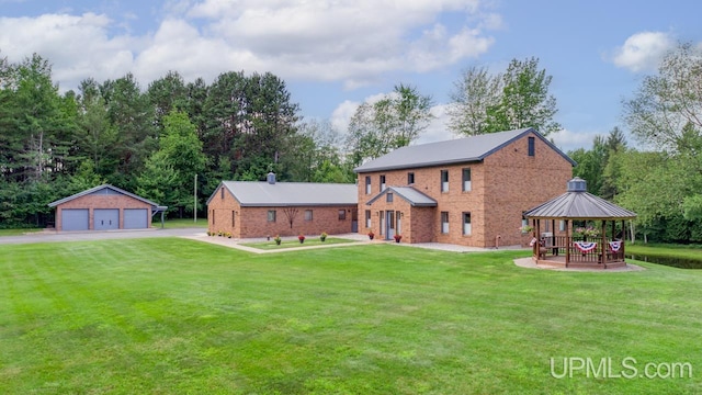 rear view of house featuring a garage, a lawn, an outbuilding, and a gazebo