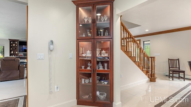 interior space with a baseboard heating unit, light tile patterned floors, and crown molding