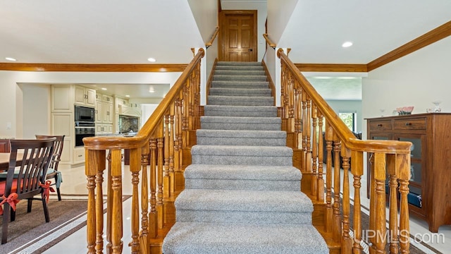 stairway featuring crown molding and light carpet