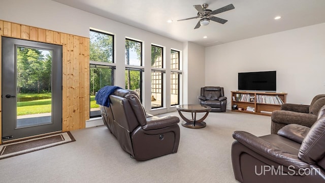 living room featuring wood walls, carpet flooring, and ceiling fan