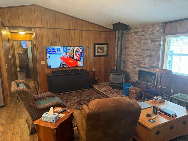 living room featuring wood walls, vaulted ceiling, a wood stove, and light hardwood / wood-style floors