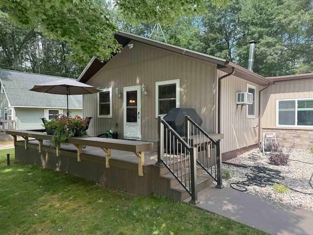 view of front of property featuring a wall mounted AC, a front lawn, and a deck