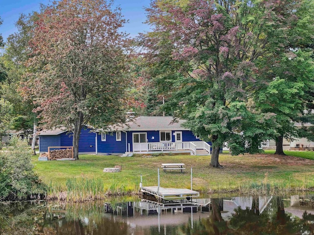 rear view of house featuring a water view and a yard