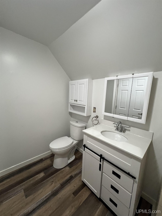 bathroom with lofted ceiling, hardwood / wood-style floors, vanity, and toilet