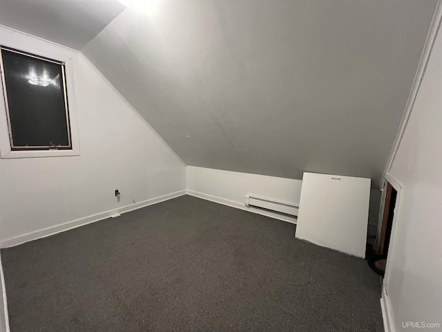 additional living space with lofted ceiling, a baseboard heating unit, and dark colored carpet