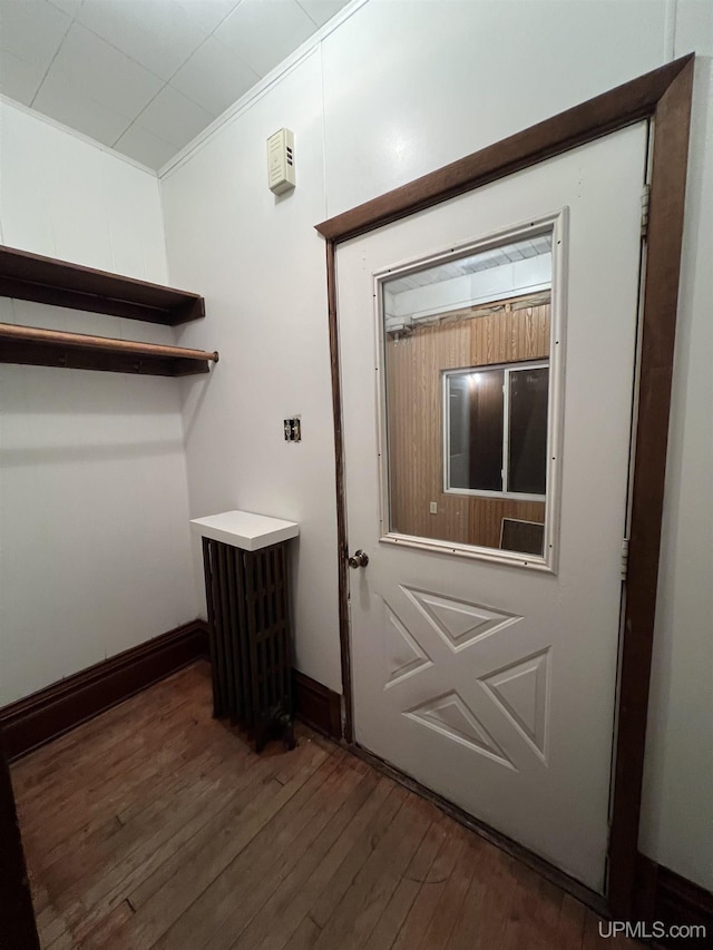 doorway to outside with ornamental molding and dark hardwood / wood-style flooring