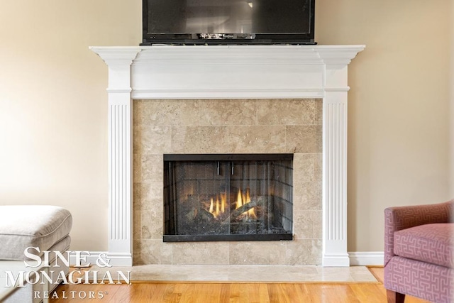 interior details featuring a tiled fireplace and hardwood / wood-style flooring