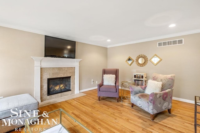 living room featuring crown molding, light hardwood / wood-style floors, and a tile fireplace