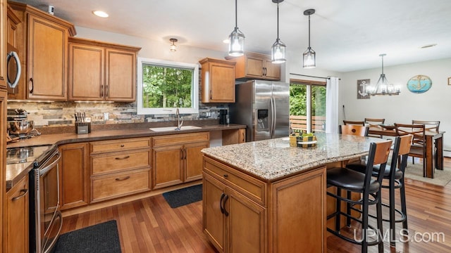 kitchen with sink, decorative light fixtures, a center island, dark hardwood / wood-style floors, and stainless steel appliances