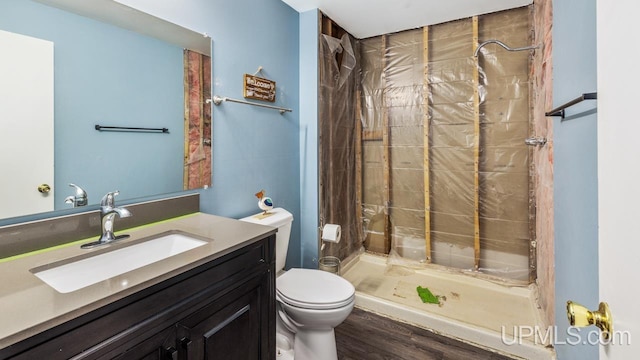 bathroom with hardwood / wood-style flooring, walk in shower, vanity, and toilet