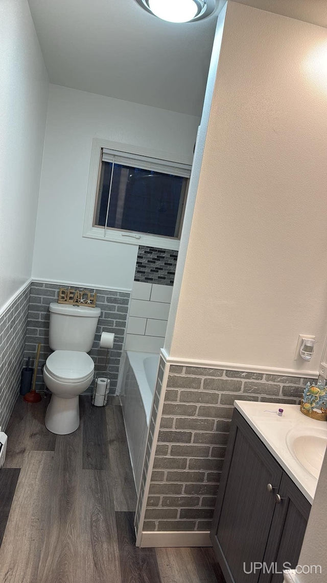 bathroom with toilet, tile walls, vanity, a bathing tub, and hardwood / wood-style flooring