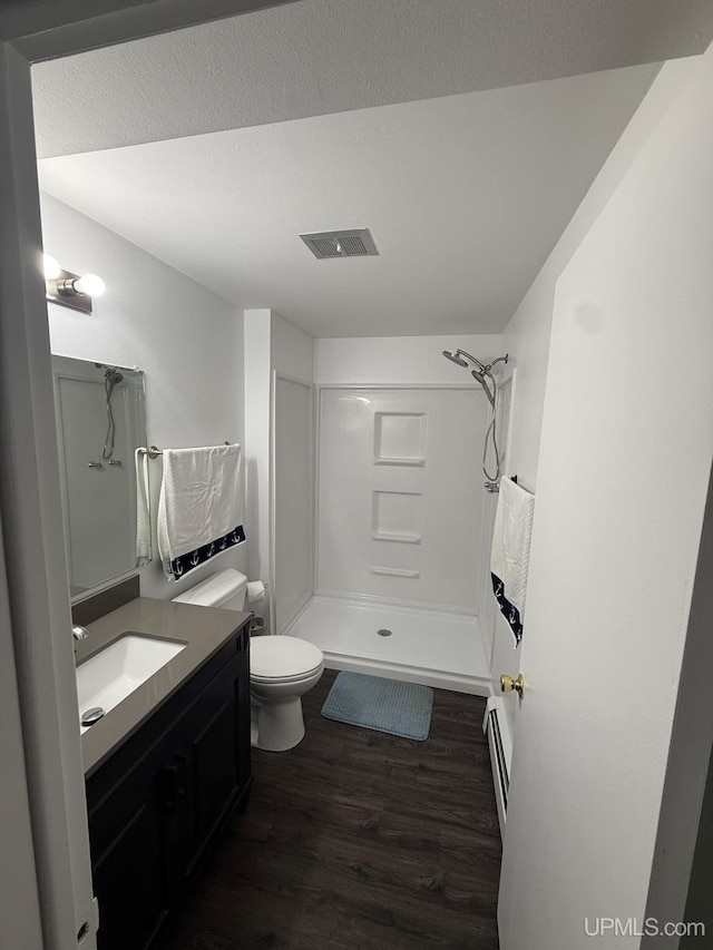 bathroom featuring a baseboard radiator, wood-type flooring, vanity, walk in shower, and toilet