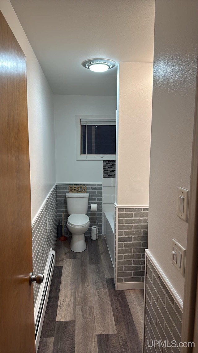 bathroom with hardwood / wood-style flooring, toilet, and a baseboard heating unit