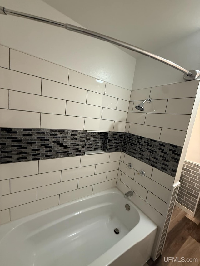 bathroom with hardwood / wood-style floors and tiled shower / bath