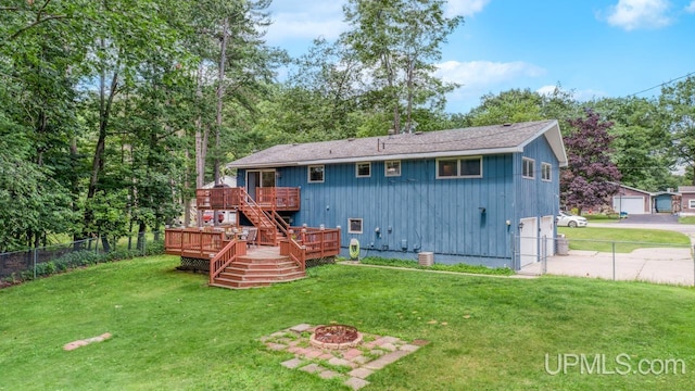 rear view of house with a wooden deck, an outdoor fire pit, and a yard