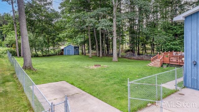 view of yard with a storage shed, a deck, and an outdoor fire pit