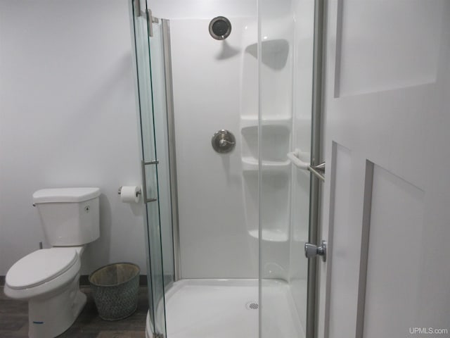 bathroom featuring a shower with shower door, toilet, and hardwood / wood-style flooring