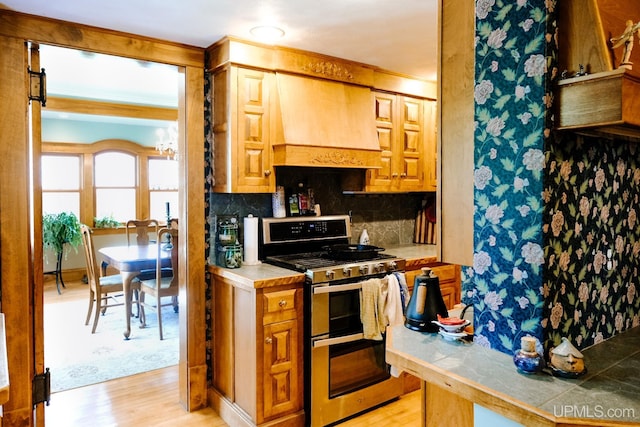 kitchen featuring range with two ovens, custom range hood, decorative backsplash, tile countertops, and light wood-type flooring