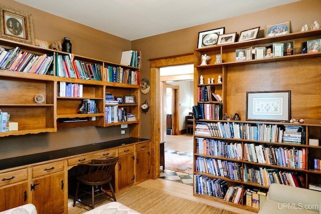 home office with built in desk and light hardwood / wood-style floors