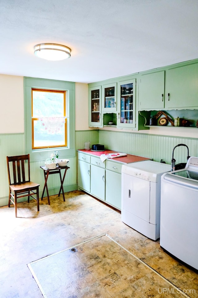 clothes washing area with cabinets, washing machine and clothes dryer, and wood walls