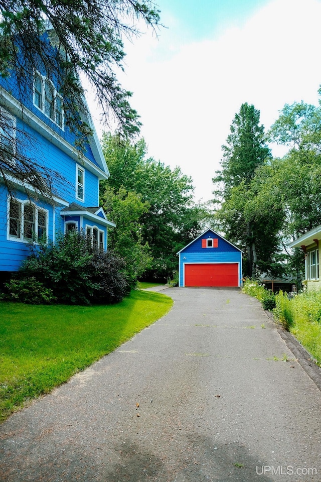 exterior space featuring a garage, a yard, and an outbuilding