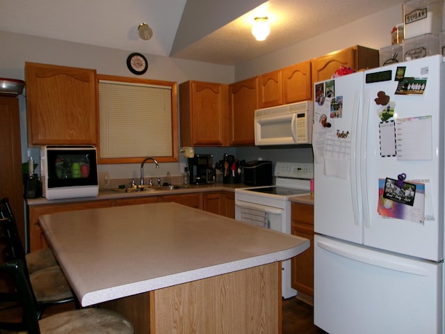 kitchen with sink, white appliances, a kitchen bar, and a kitchen island