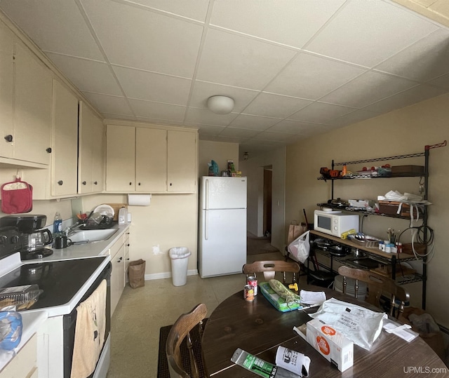 kitchen featuring sink, a paneled ceiling, white appliances, and cream cabinetry