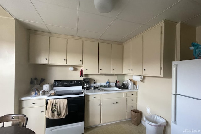 kitchen with sink, a drop ceiling, range with electric stovetop, white refrigerator, and cream cabinetry