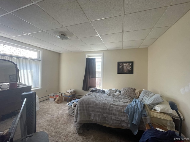 bedroom featuring a baseboard heating unit, carpet floors, and a drop ceiling