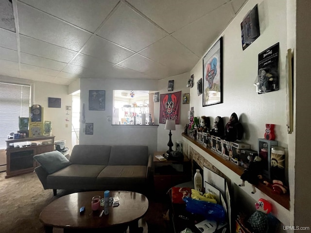 living room featuring a drop ceiling and carpet