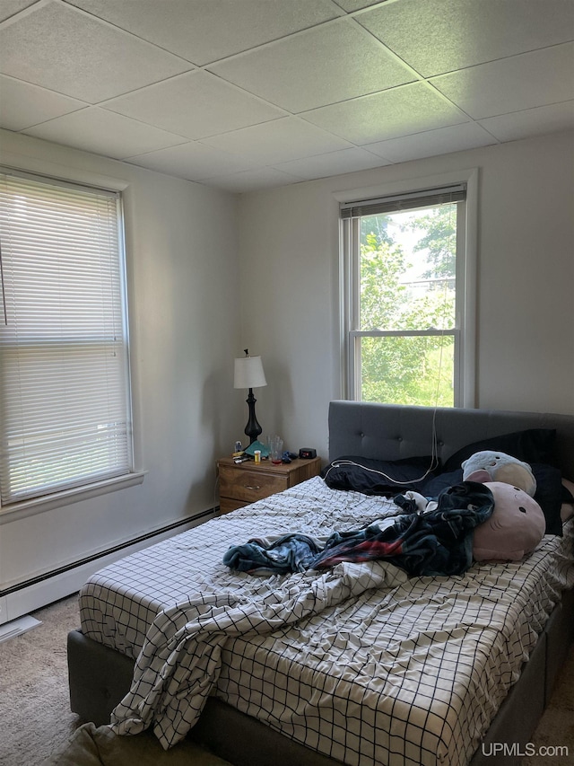 carpeted bedroom with a baseboard radiator and a paneled ceiling